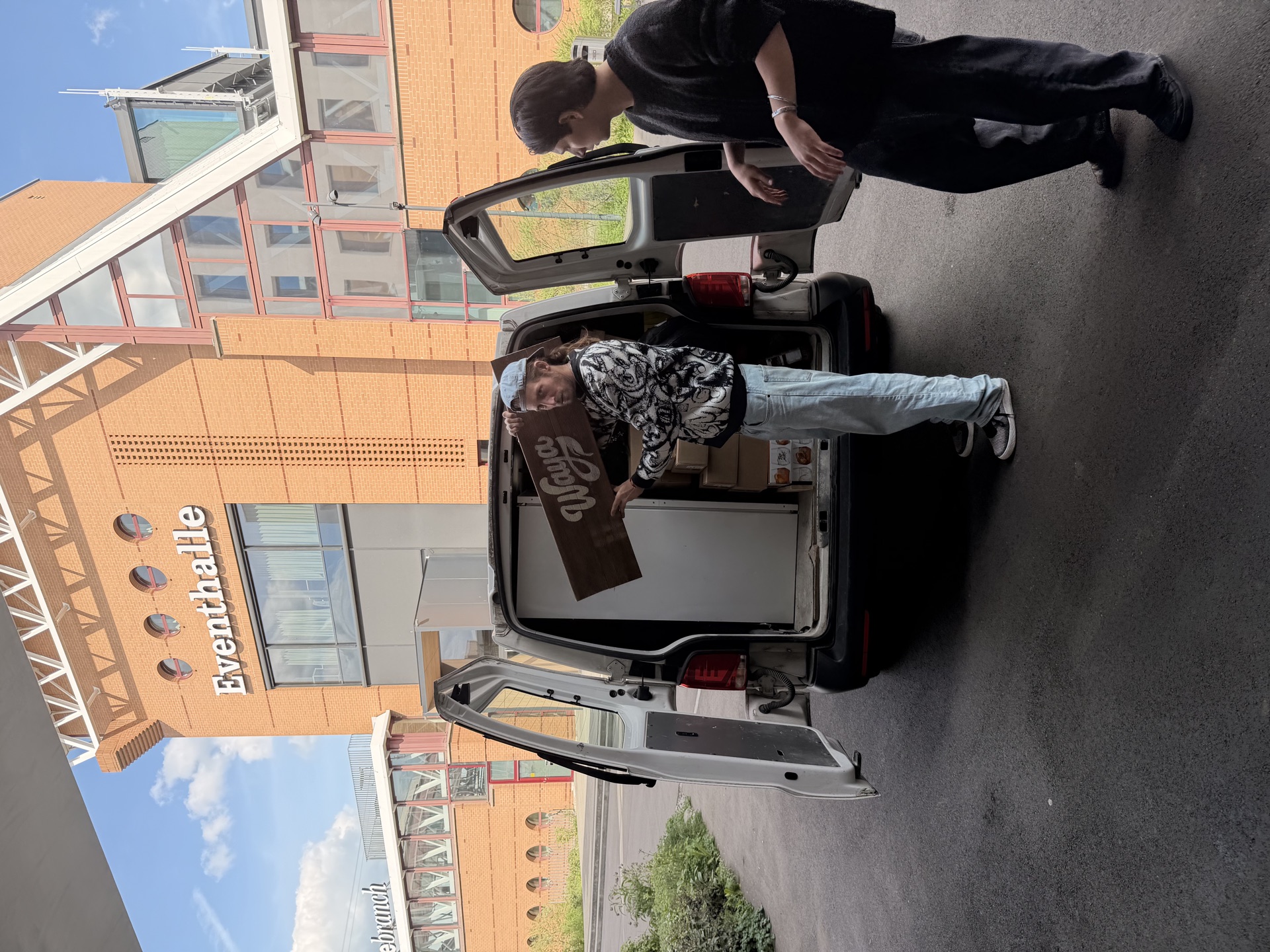 WAYA Van wird mit Dosen und Holzschild vor der Eventhalle beladen